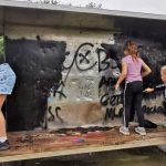 Young people painting the shelter black