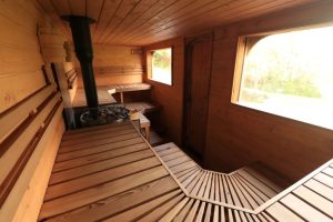 Cozy interior of Finnish-inspired wood-fired sauna at Stone & Steam Community Sauna, Hartcliffe City Farm Bristol – cedar benches, stove, and natural light views