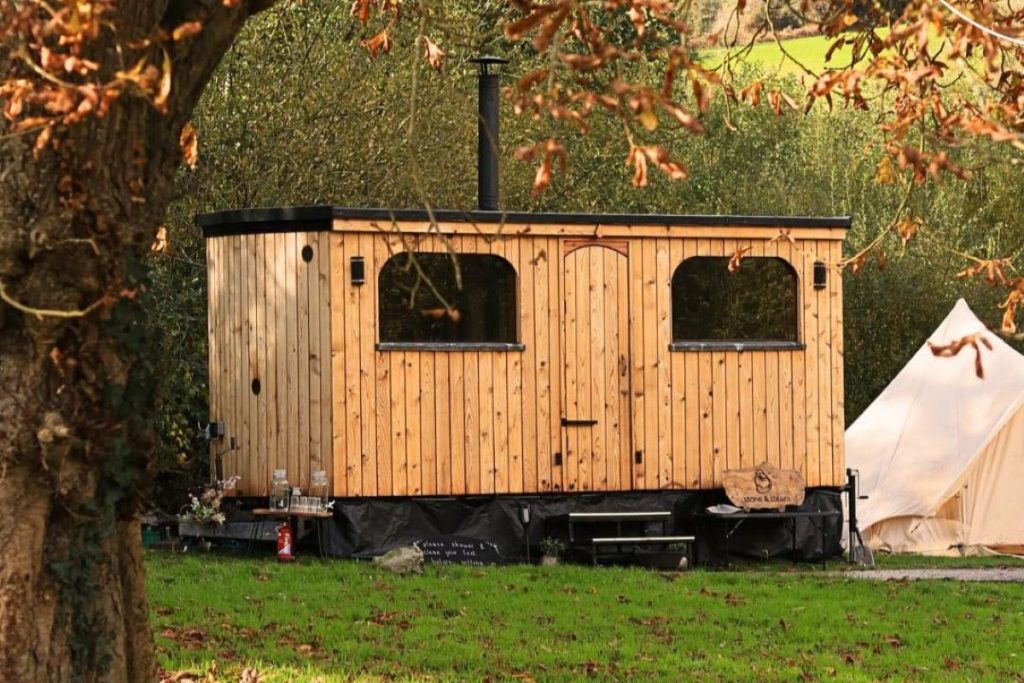 Wood-fired community sauna exterior at Stone & Steam, nestled in woodland glade at Hartcliffe City Farm, Bristol – inviting cedar cabin in nature